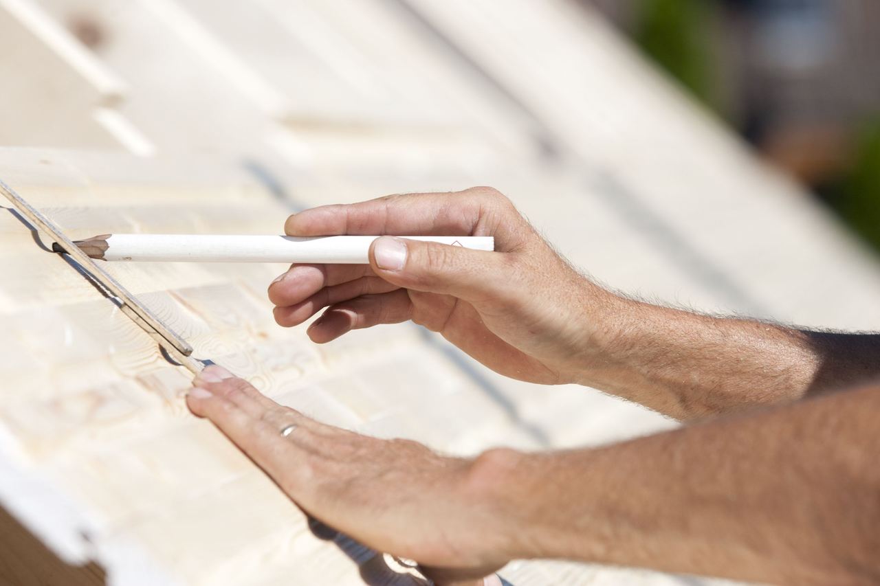 Hand zeichnet mit Bleistift Maße auf ein Holzbauteil